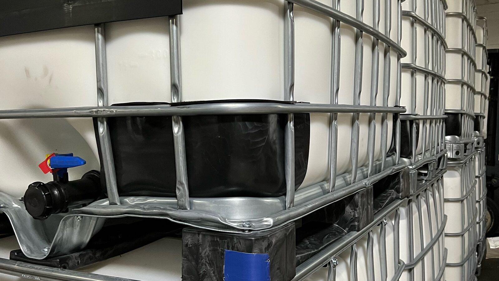 Stacked 8249C IBC totes with blue valve in the warehouse