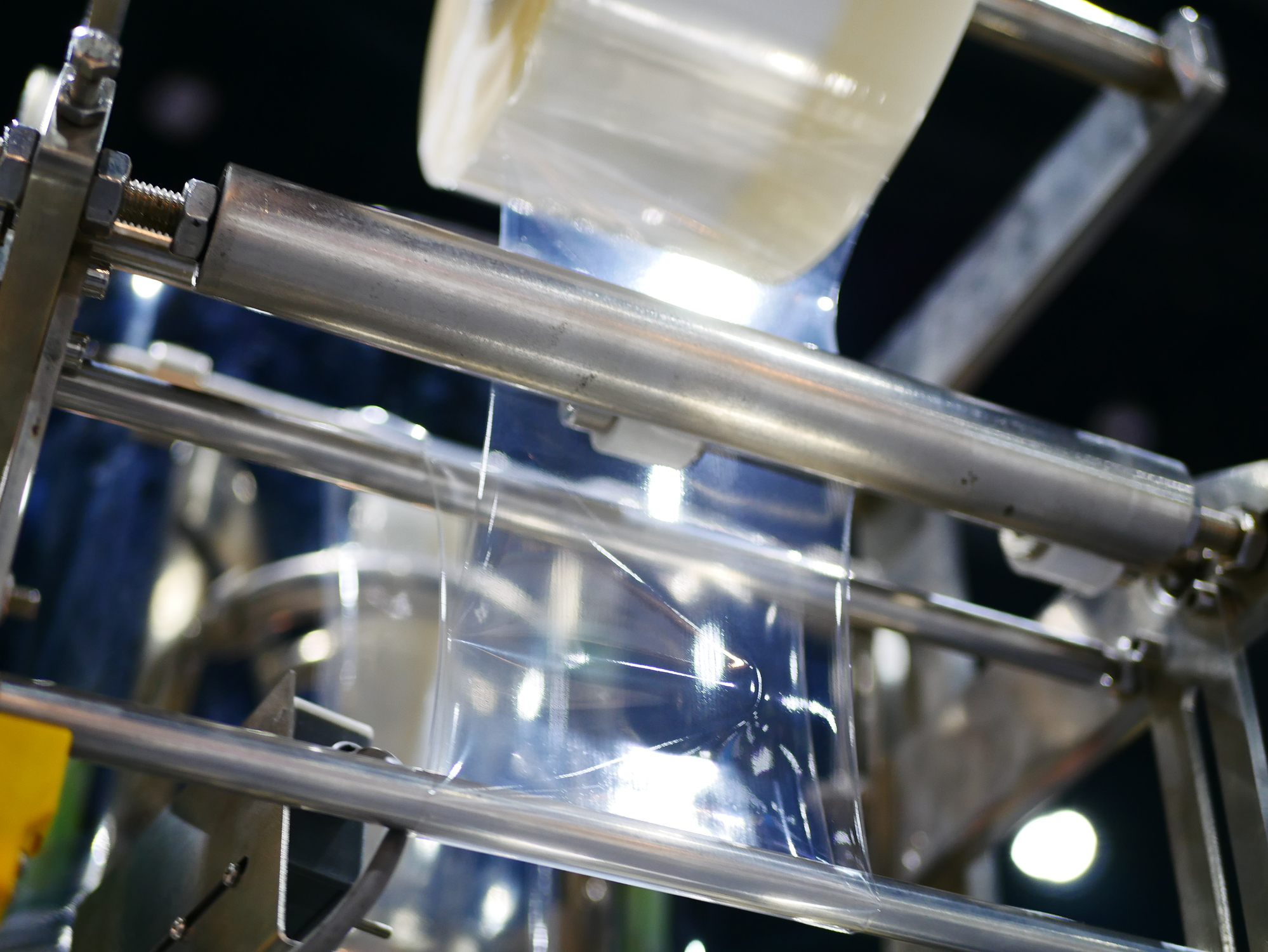 Clear adhesive film running through industrial coating rollers